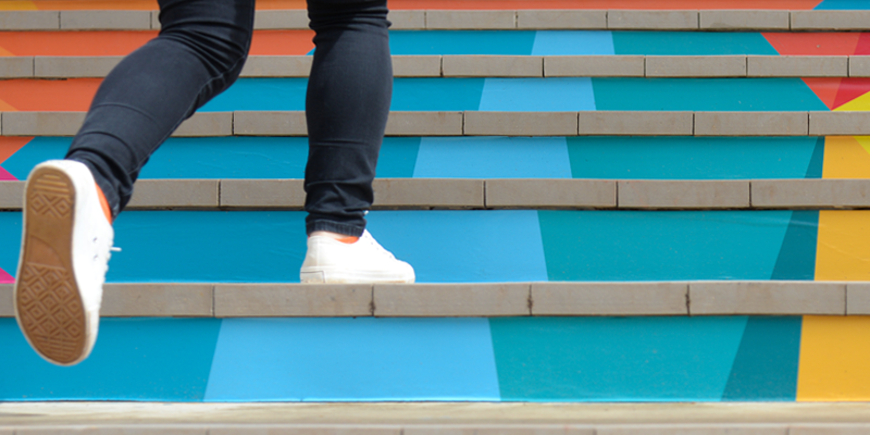 Una persona subiendo unas escaleras de colores